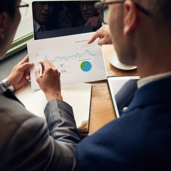 Business people analyzing visitors activity statistics, view over the shoulder
